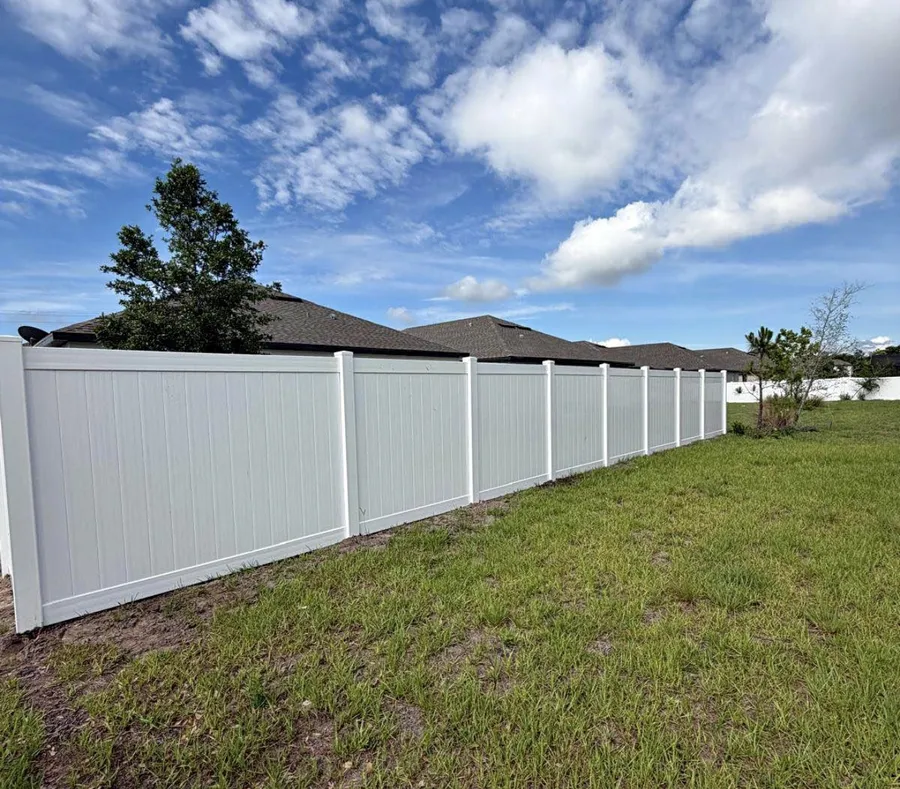 White vinyl privacy fence installed around a backyard