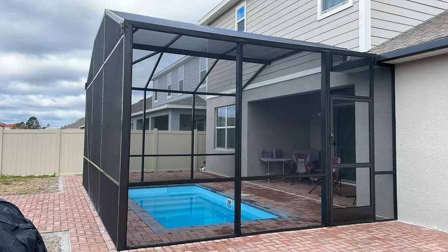 Full screen enclosure around a fiberglass pool, seen from the yard